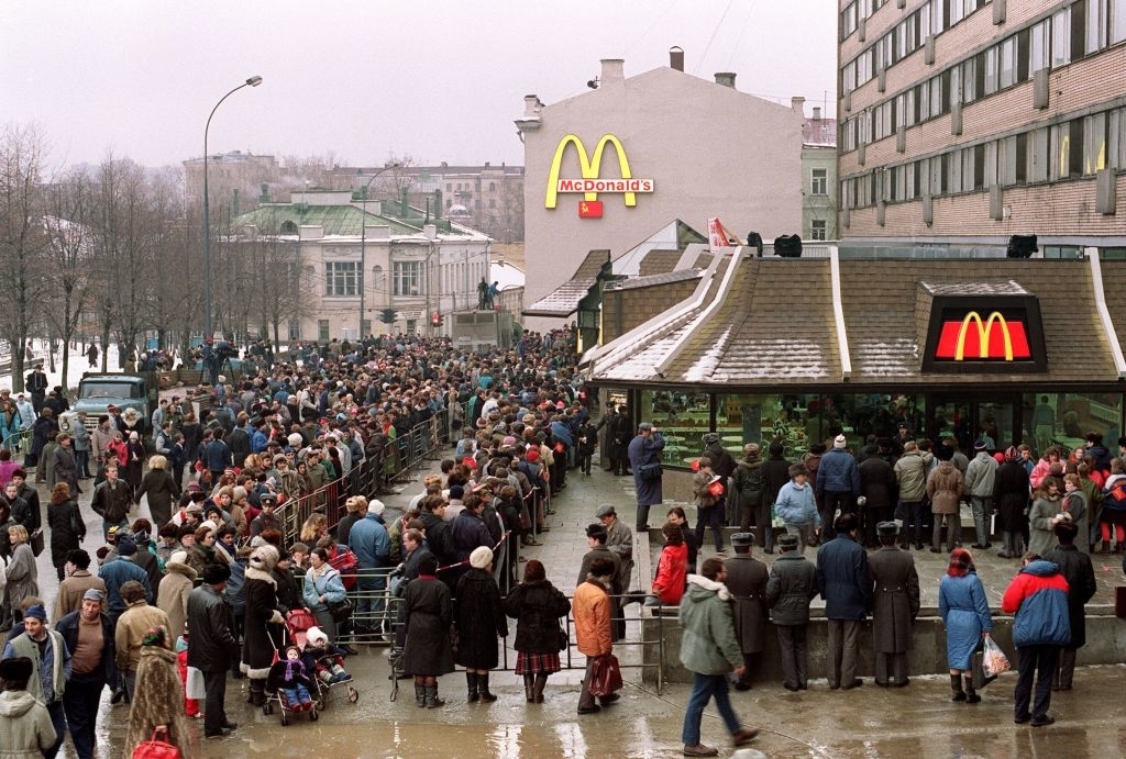 A very long, winding line extending into a bigger crowd surrounds a McDonald&#x27;s