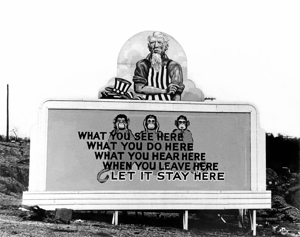 A billboard with an Uncle Sam–type figure above three monkeys (each covering their eyes, ears, or mouth) with the words, &quot;What you see here what you do here what you hear here when you leave here let it stay here&quot;