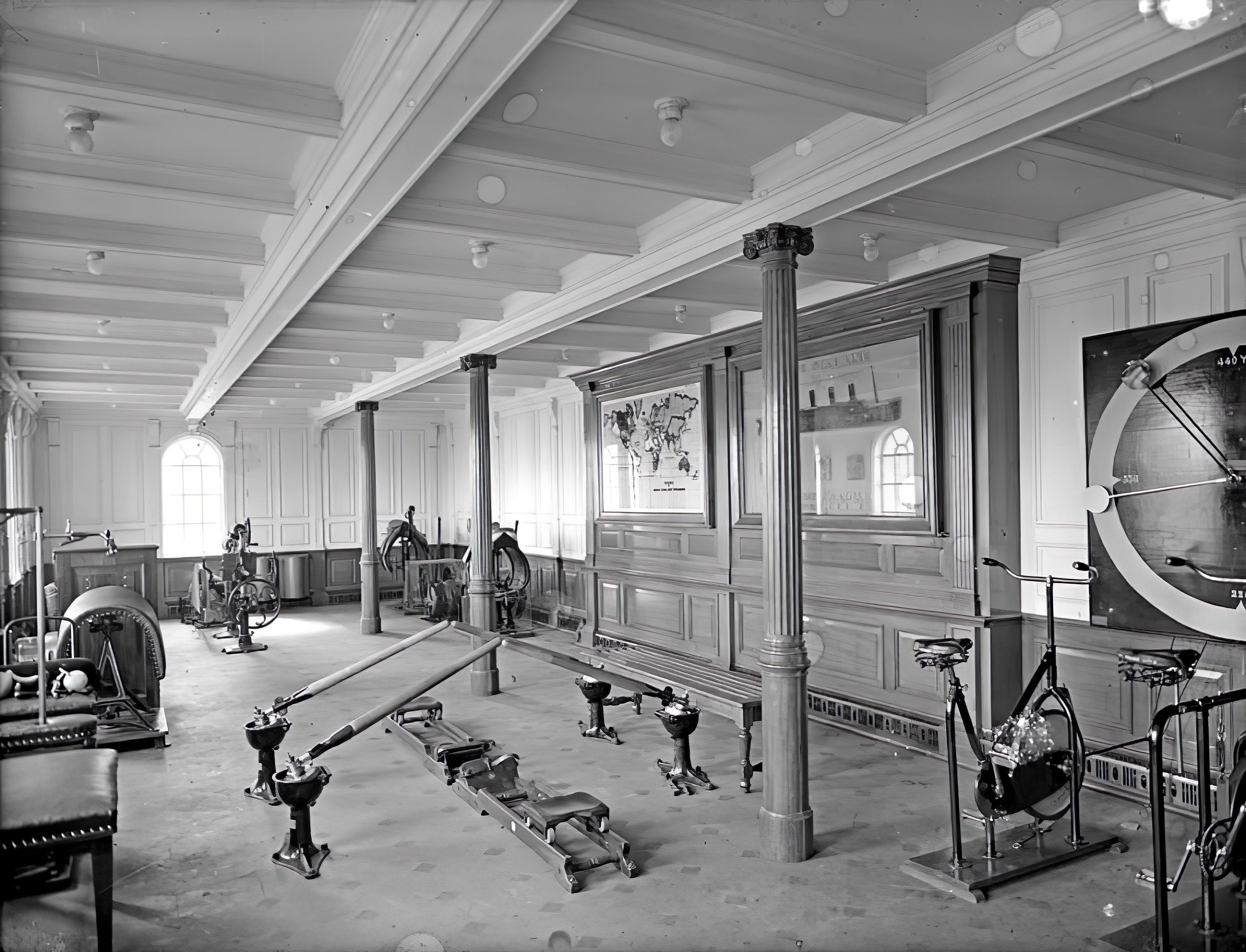 A room with wood paneling, some stationary bikes and what looks like a rowing machine