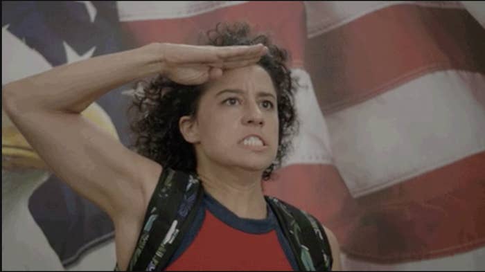 a woman saluting in front of a flag