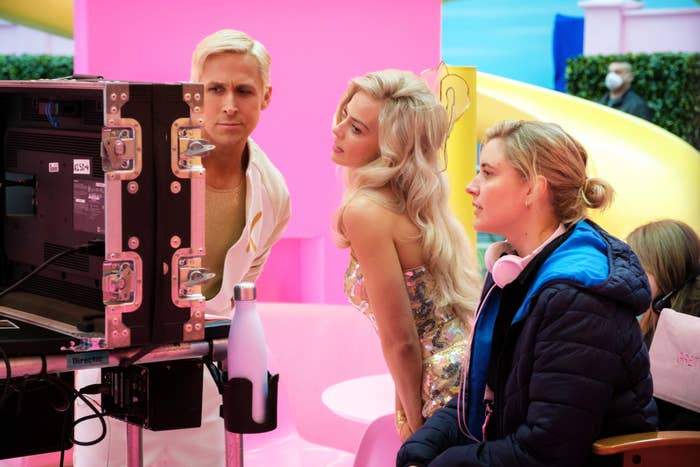 Ryan Gosling, Margot Robbie and director Greta Gerwig looking at a monitor on set
