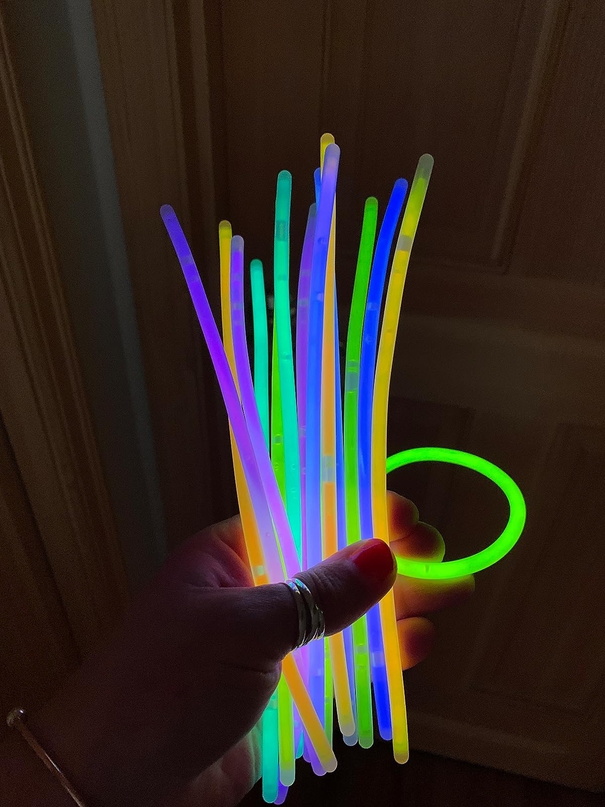 Hand holds multi-colored glow sticks