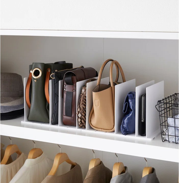 the divider in white holding handbags in a closet