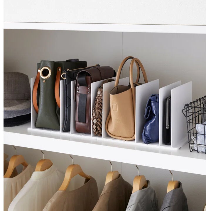 the divider in white holding handbags in a closet