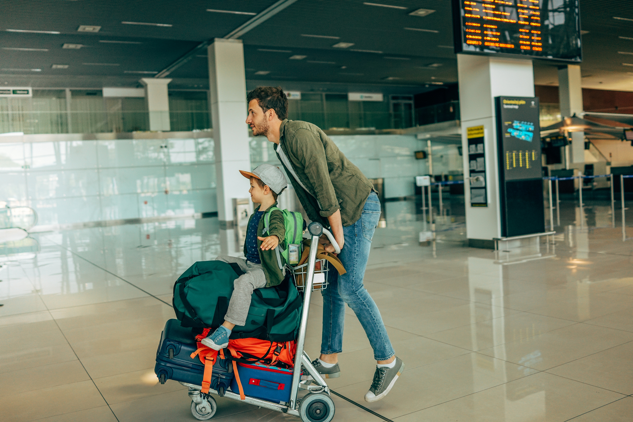 A dad pushing his son through an airport