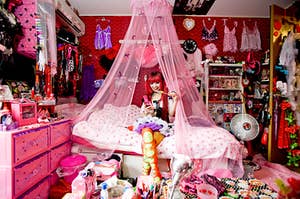 a girl sitting on her bed in a very bright, cluttered, hot pink room