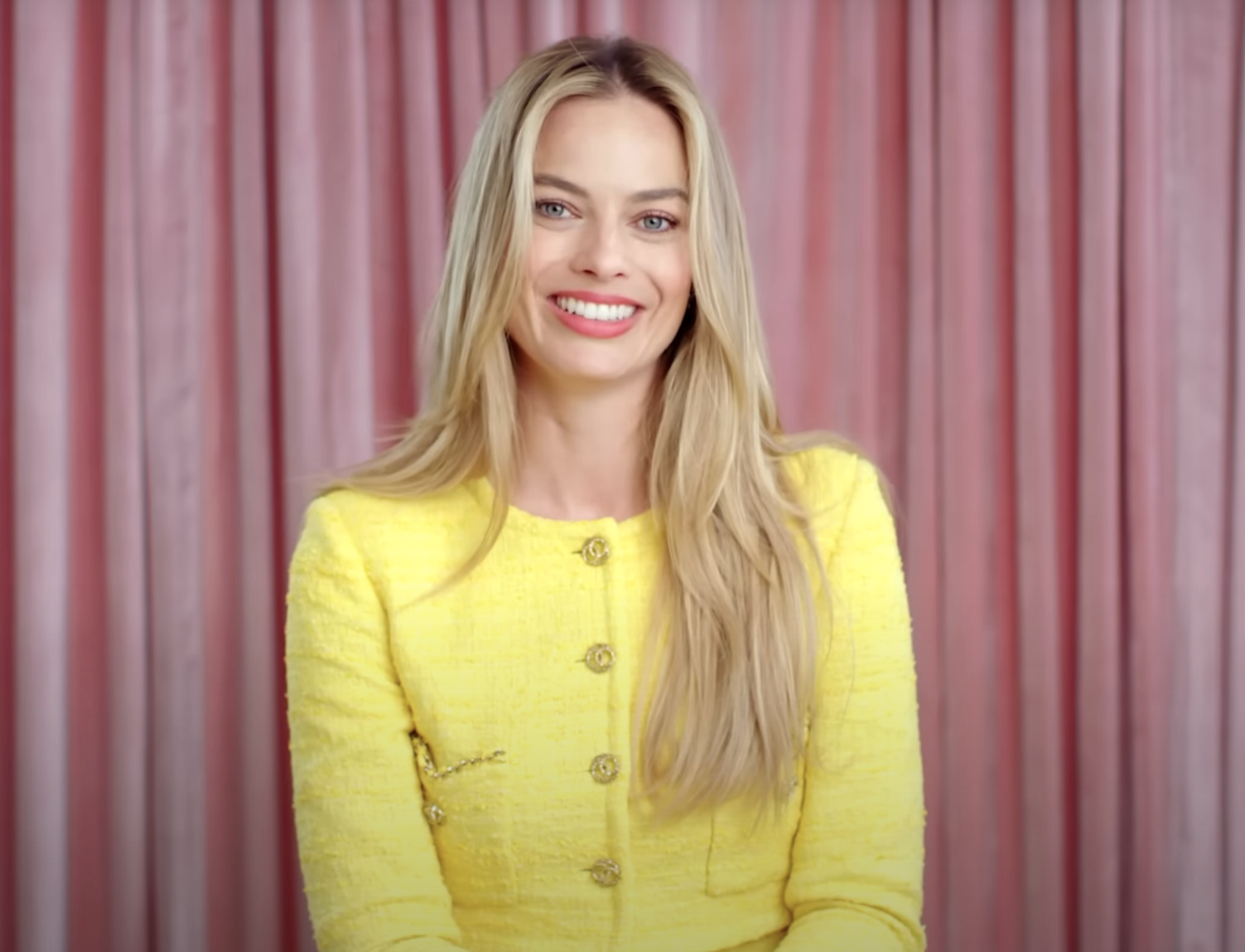 closeup of Margot Robbie in a yellow tweed outfit during an interview