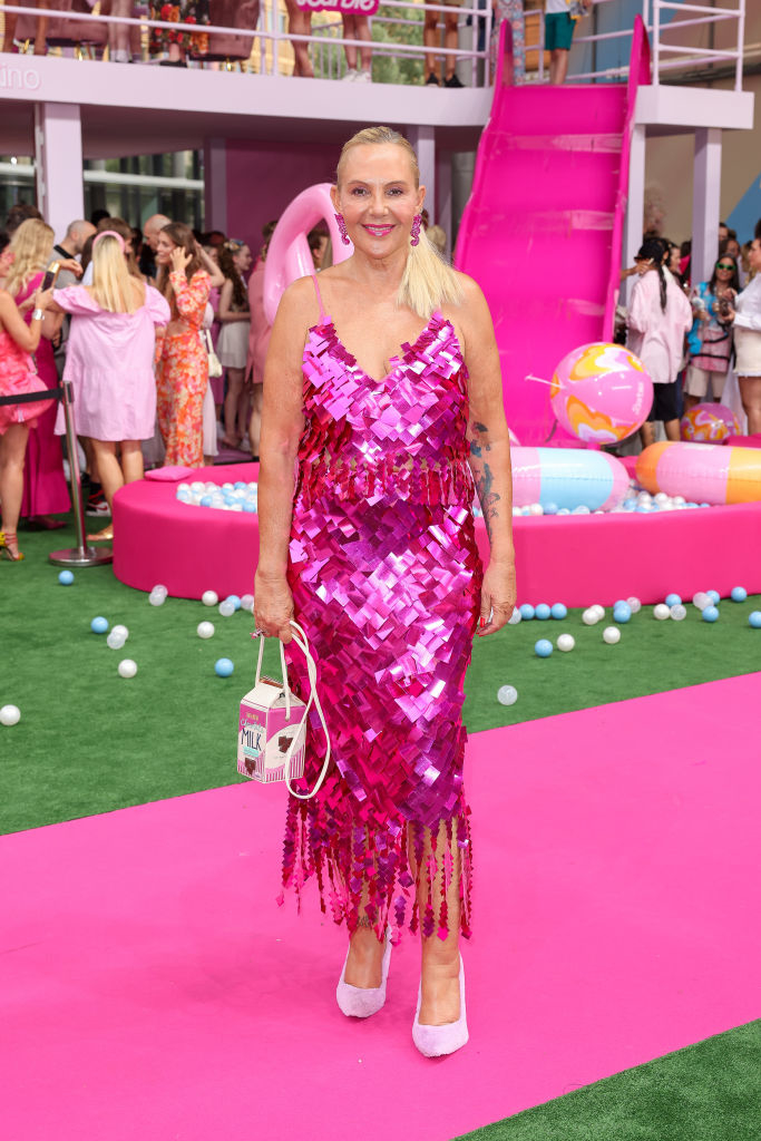 wearing a shiny spaghetti-strap dress with fringe and carrying a purse in the shape of a milk carton