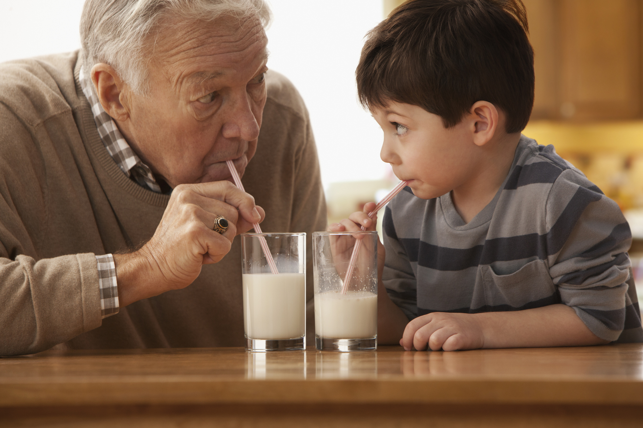 A grandpa and grandson drinking milk together