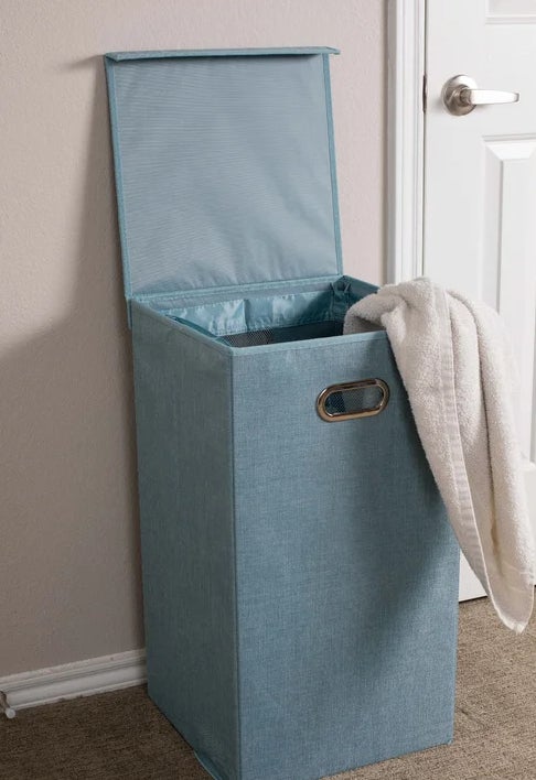 the hamper in light blue with laundry in it