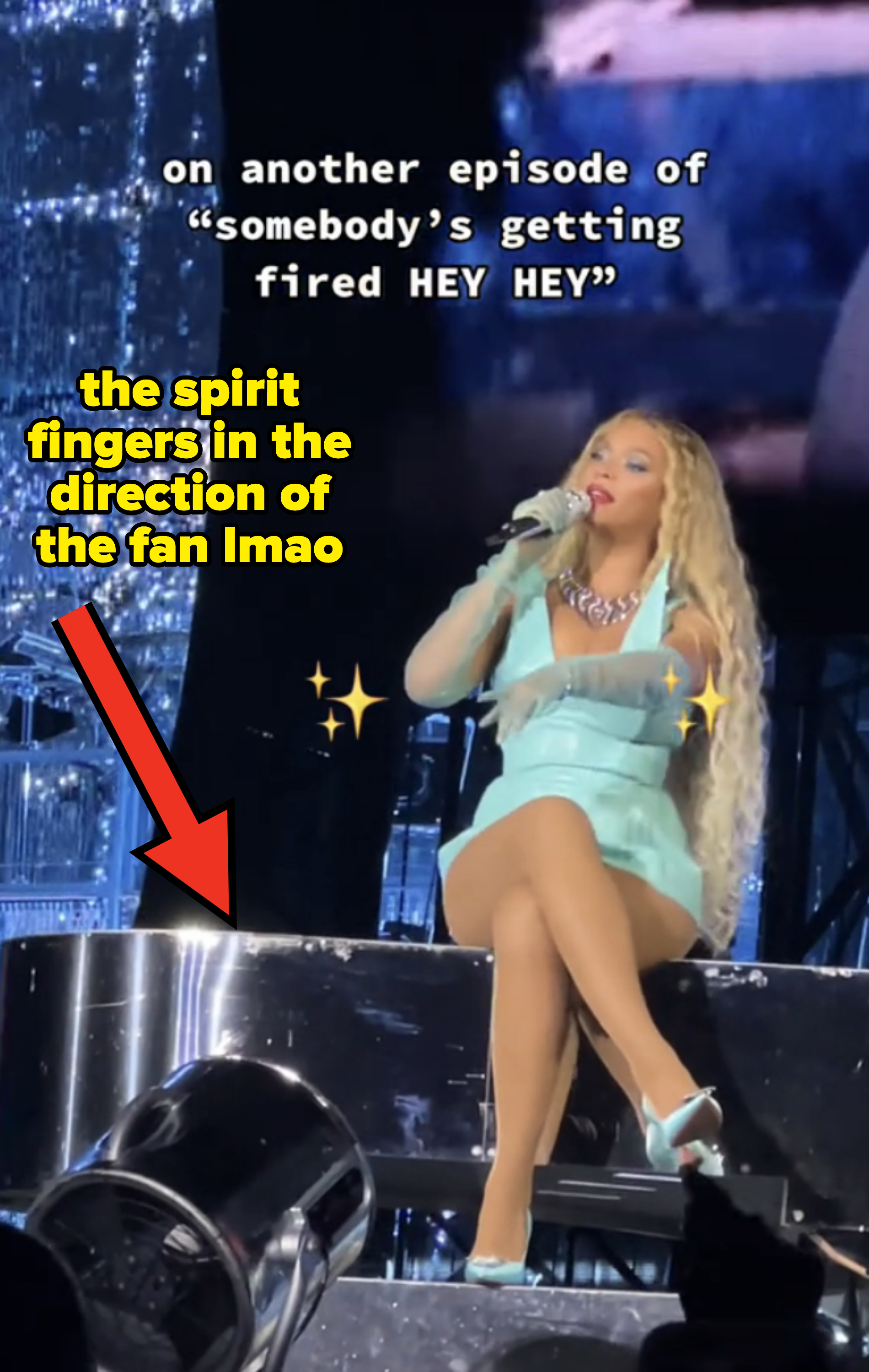 Beyoncé sitting and performing on stage and gesturing to a fan that is not on