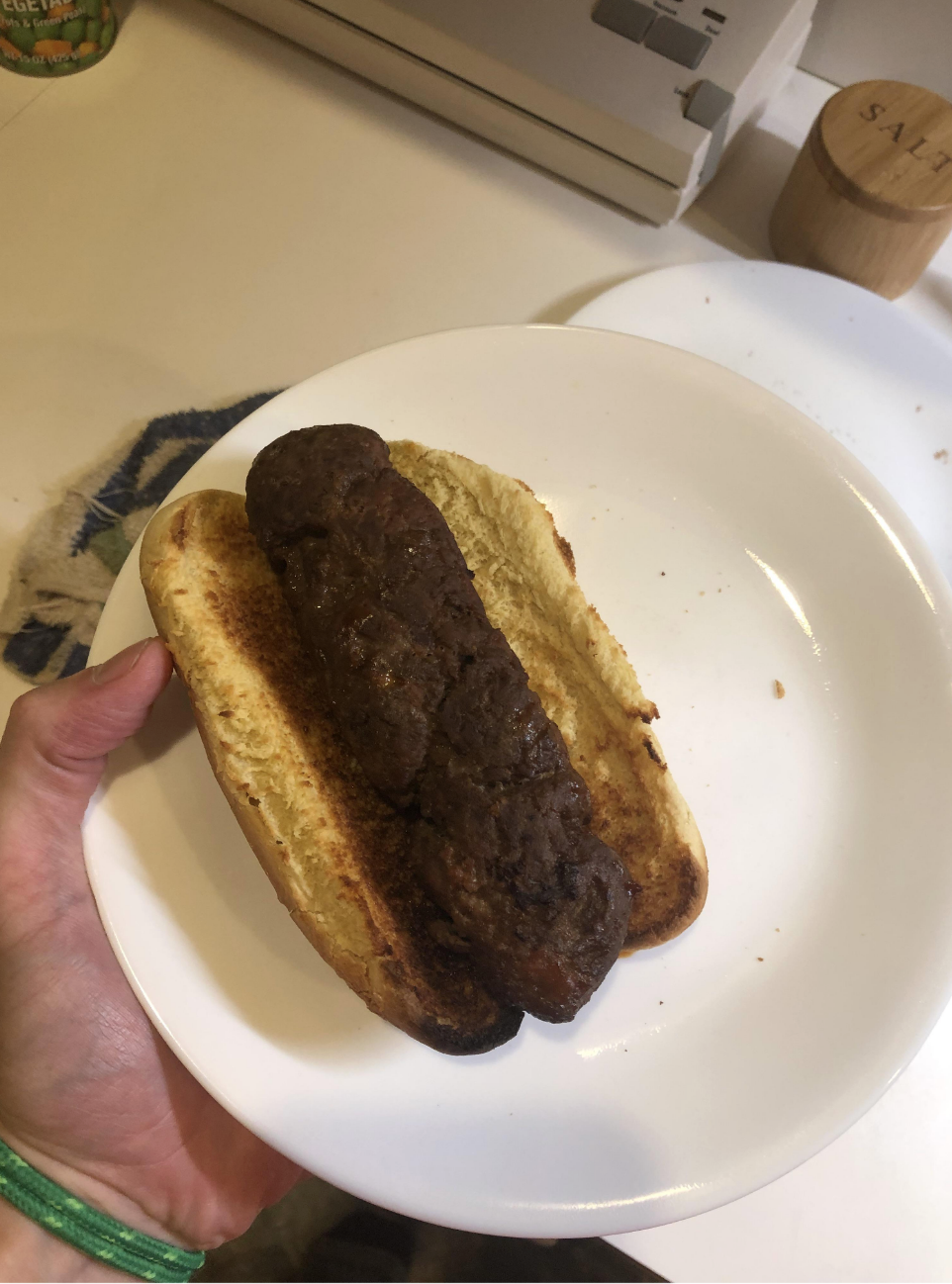 A piece of burned meat on an overly toasted bun; the meat is so badly burned, it&#x27;s impossible to tell what it even is