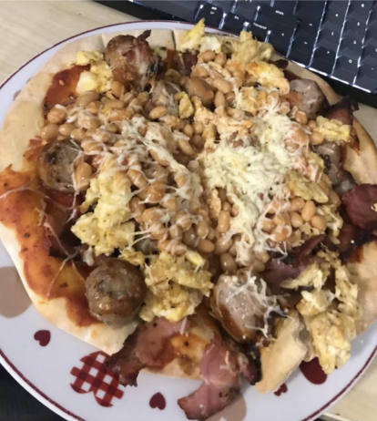 A random assortment of things have been put on top of a pizza crust; it looks like there&#x27;s lettuce, sausage, corn, and shredded cheese among the toppings