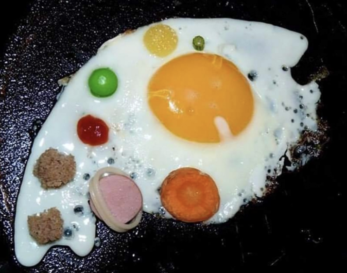 The egg whites ran a little, so the person placed things like carrots, sausage, and ketchup in the whites to make it look like the yolk is the sun and the random things are planets