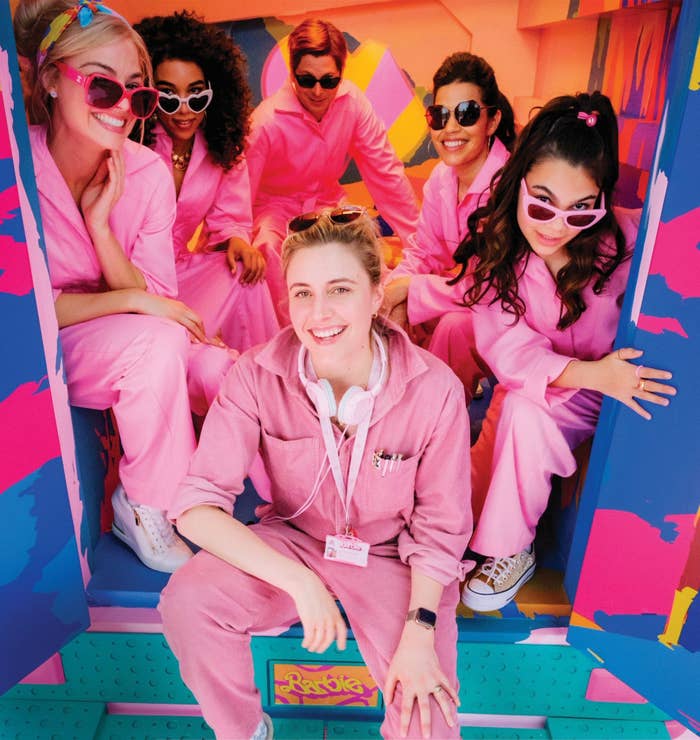 cast of barbie with greta posing in the back of a truck wearing the same jumpsuits