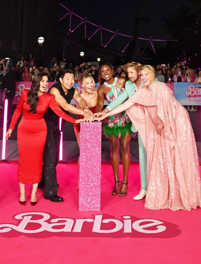 The cast of &quot;Barbie&quot; at a premiere with their arms outstretched to press a button together