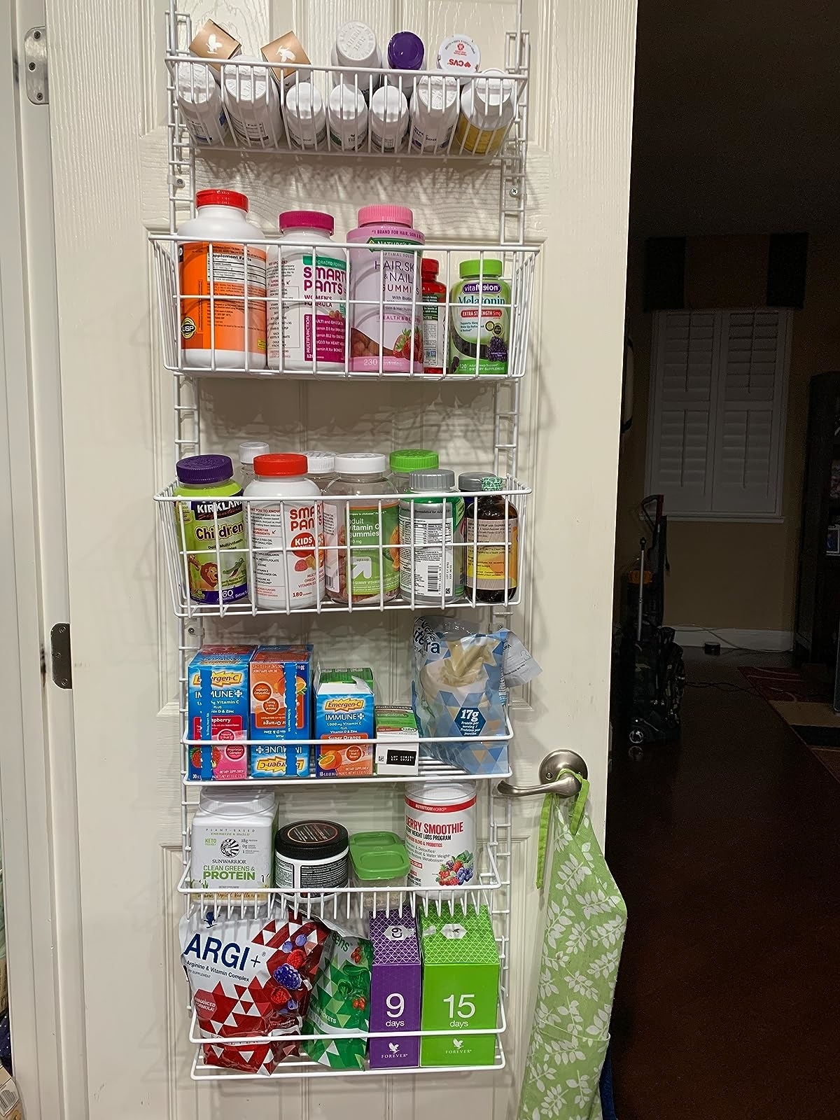 Reviewer image of the organizer filled with vitamins and supplements hanging on the door
