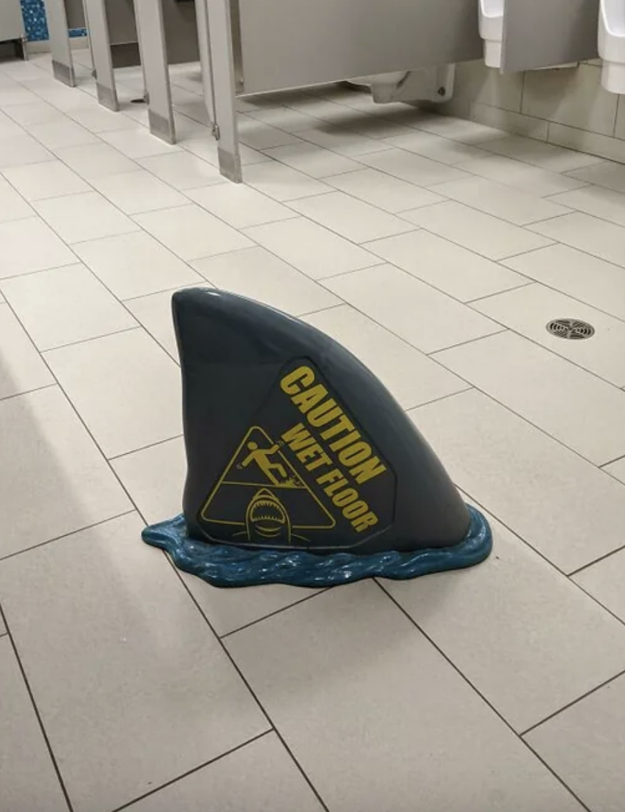 A &quot;wet floor&quot; sign in the shape of a shark&#x27;s fin
