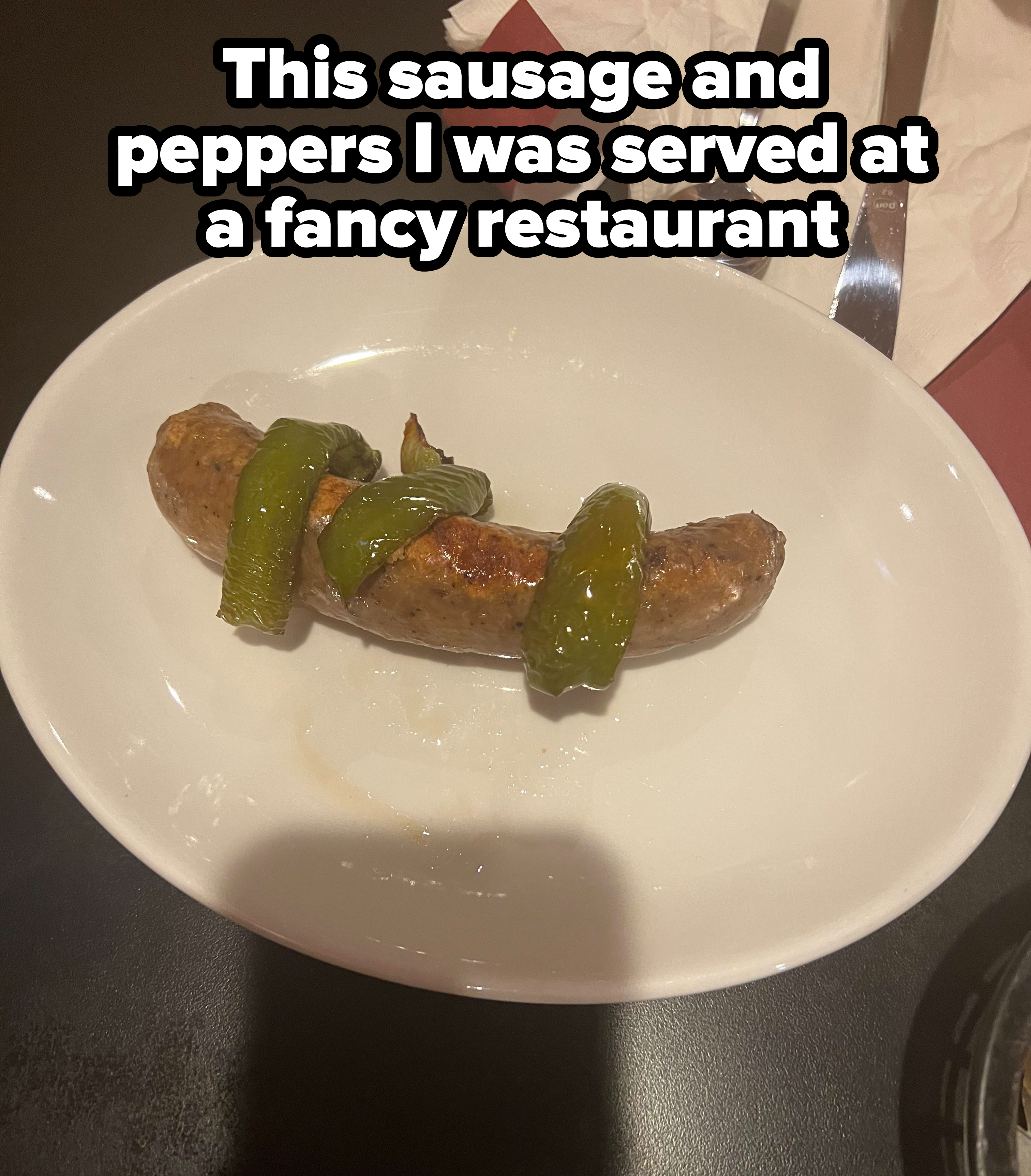 A piece of sausage with three green peppers on top