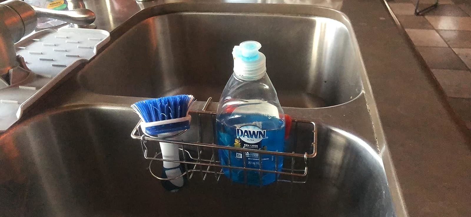 Reviewer image of a brush and dish soap bottle in holder over their sink