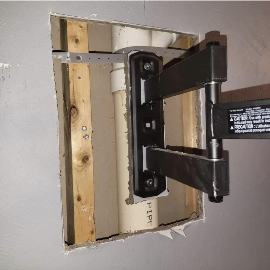 A TV mounting kit attached to a pipe through the wall