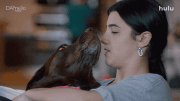 GIF of a young woman kissing her dog