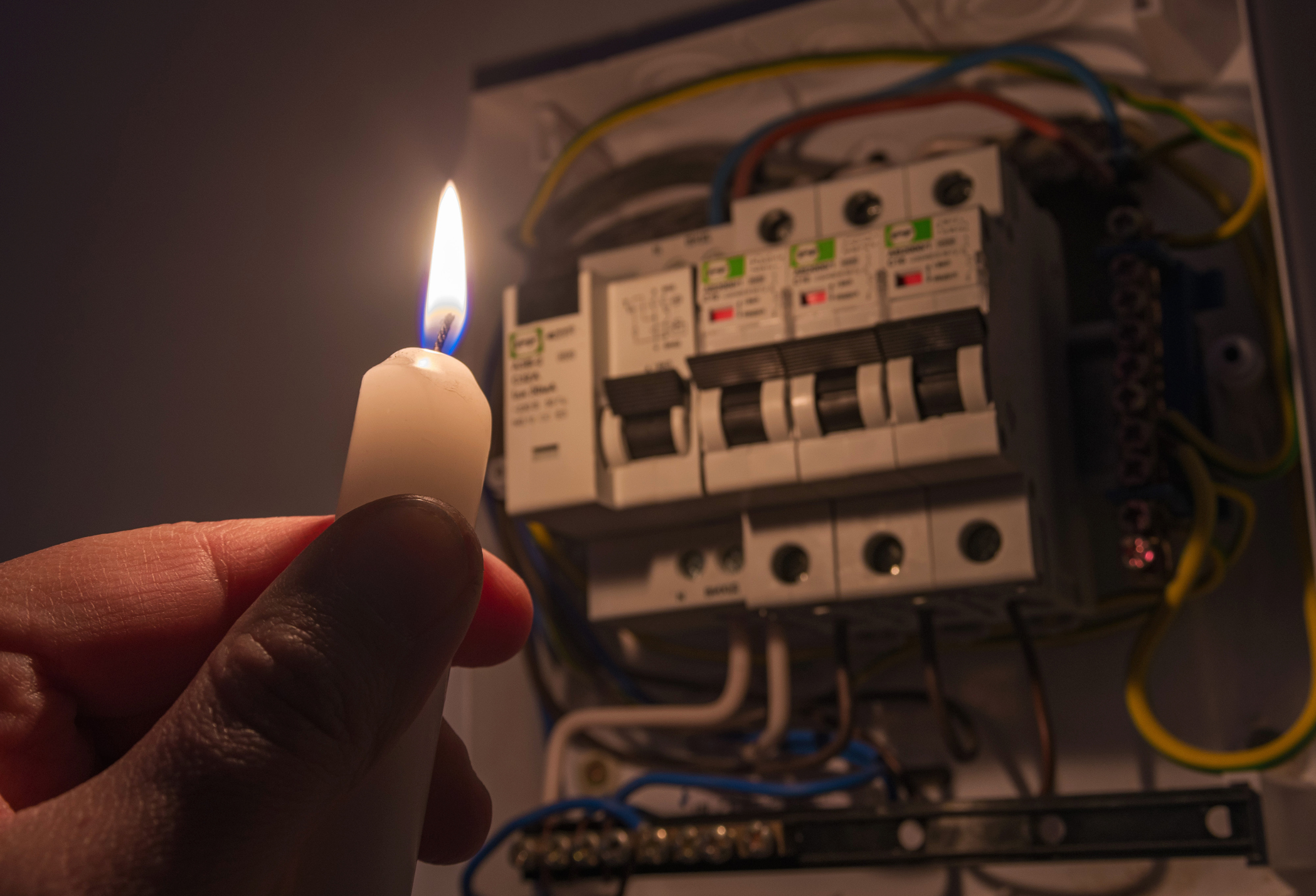 Someone holding a candle up to a fuse box