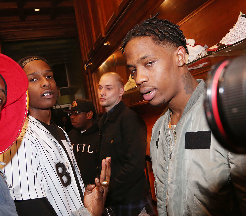 A$AP Rocky and Travis Scott standing next to each other as a camera is pointed at them and others