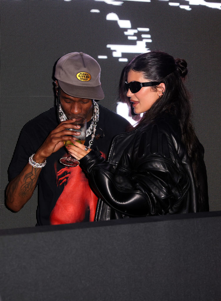 Travis taking a sip of a drink Kylie is holding