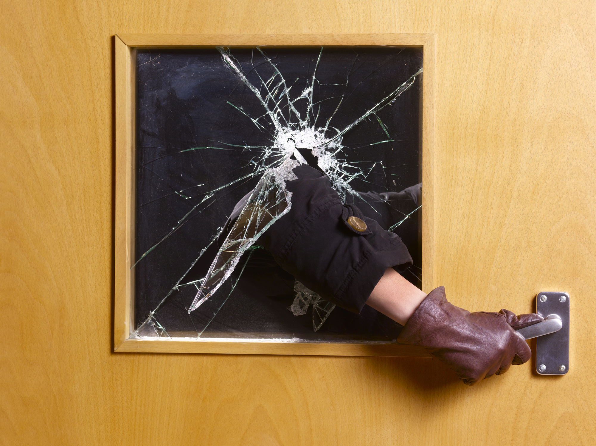 hand through a broken window grabbing the door handle