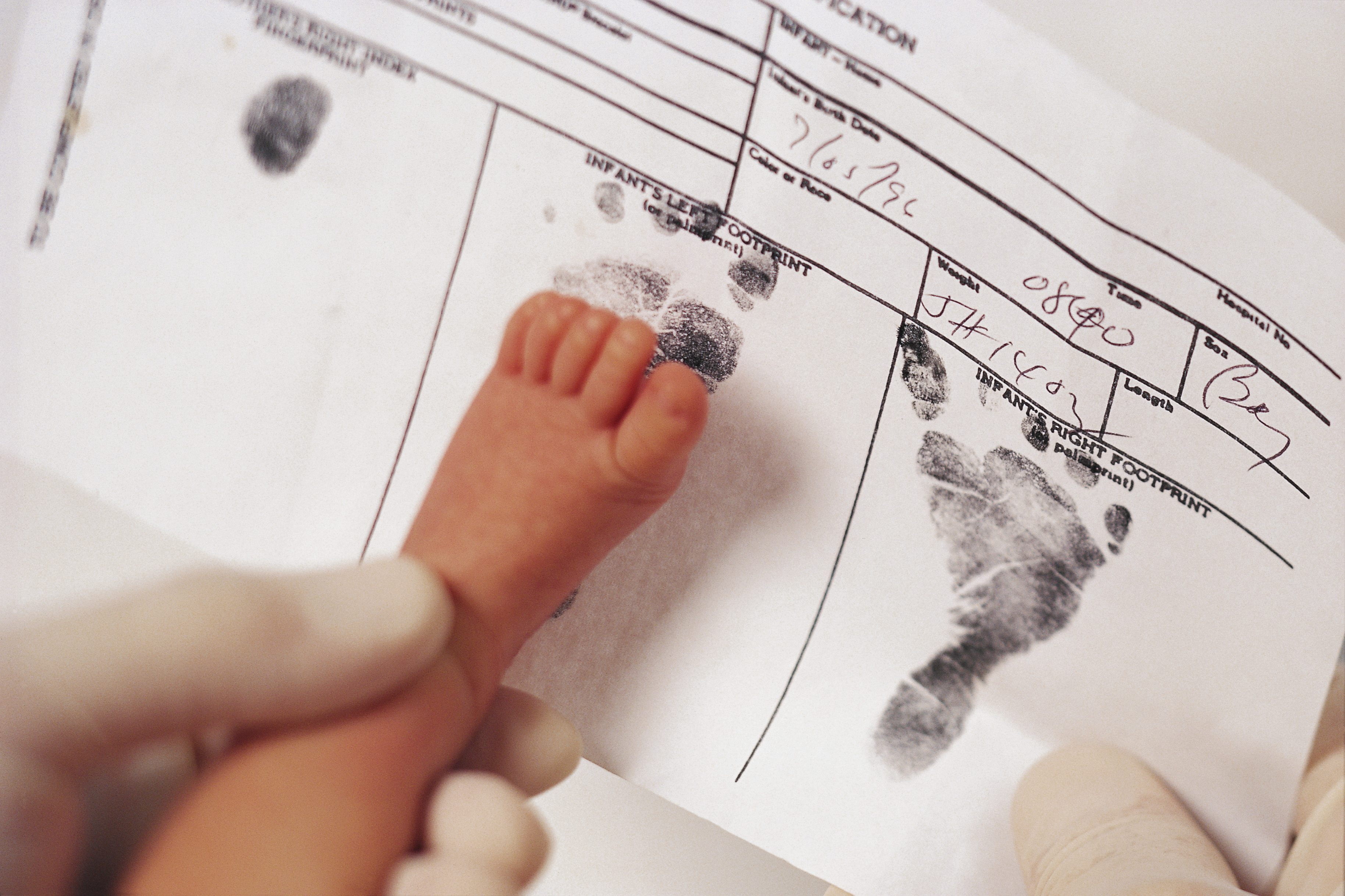 Newborn stamping footprint on birth certificate