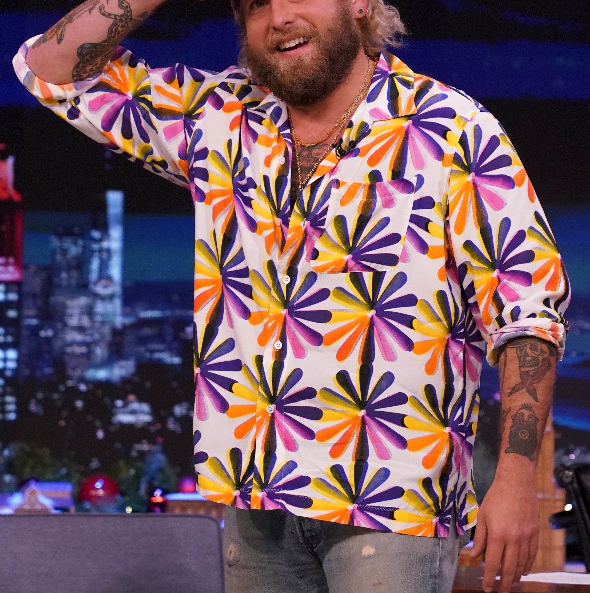 Close-up of Jonah in a bright print shirt and saluting on a talk show