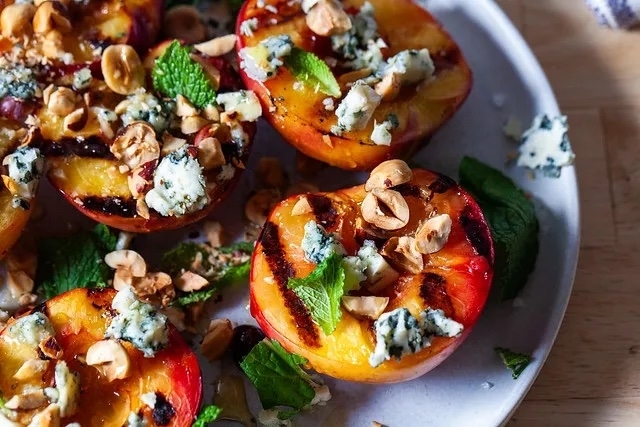 Plated grilled nectarines topped with gorgonzola and hazelnuts
