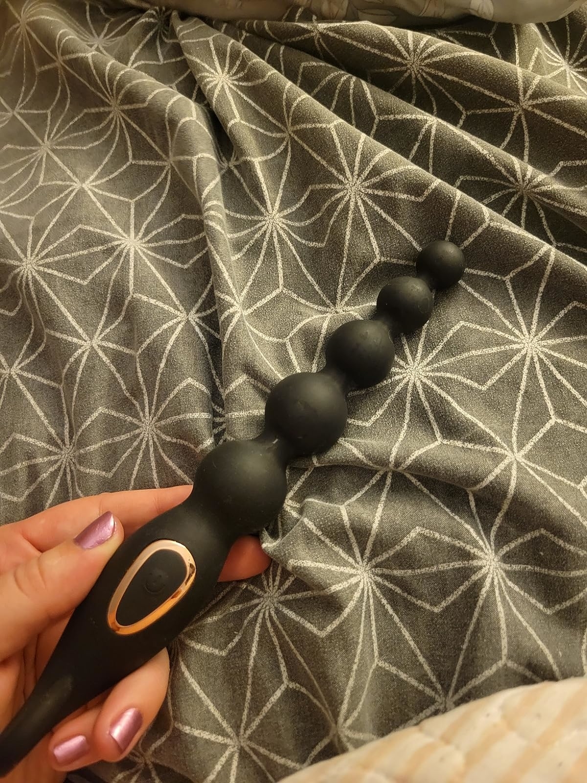 Reviewer holding black vibrating anal beads