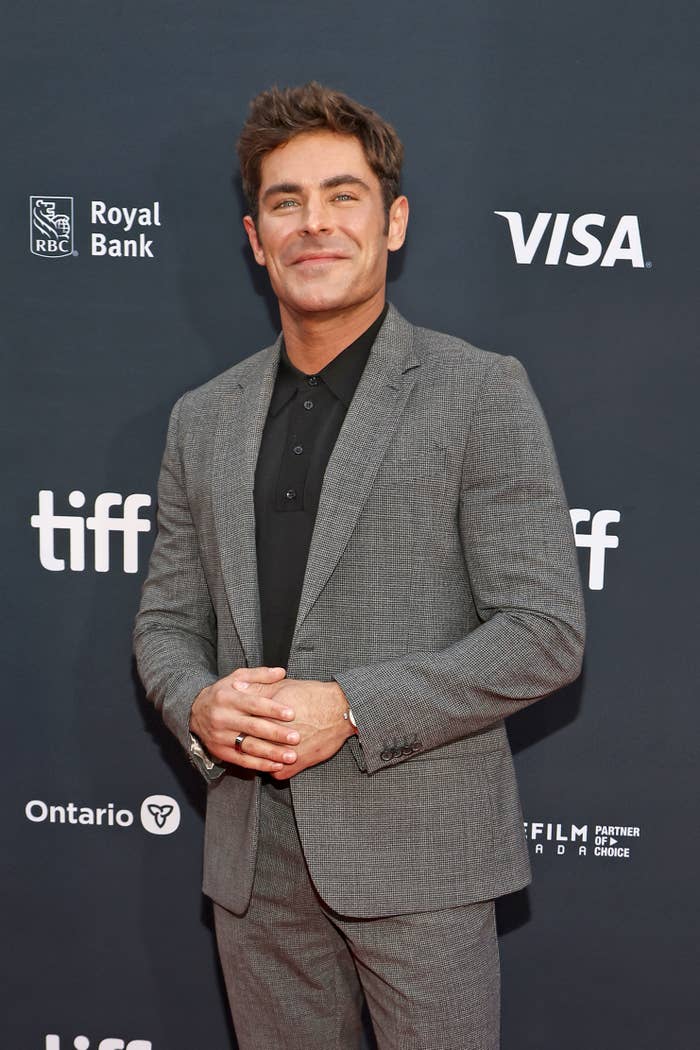 A closeup of zac efron wearing a suit for a film fest event as he smiles on the red carpet