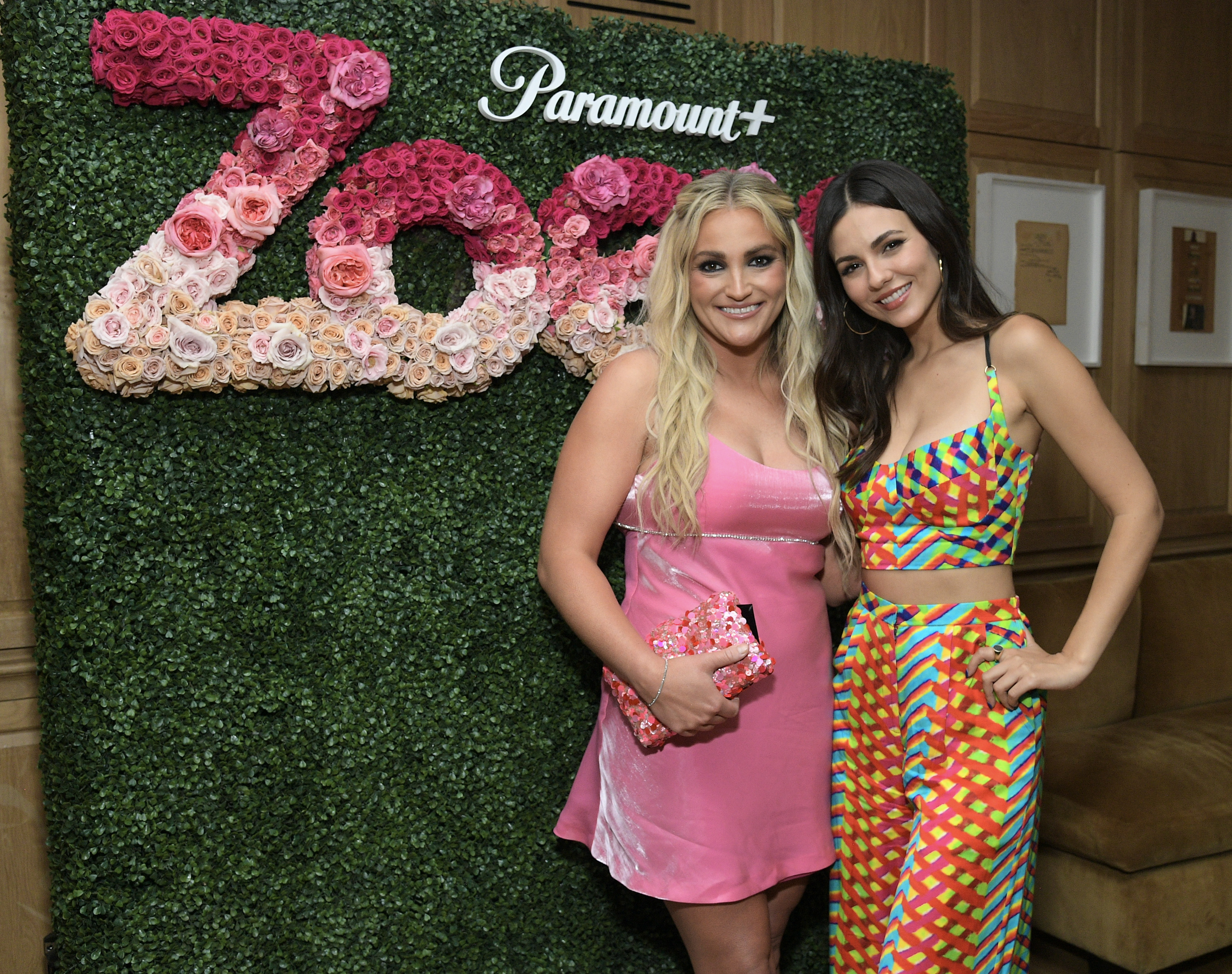 An adult JamieLynn Spears and Victoria Justice pose for a photo in front of a floral arrangement that spells out Zoey