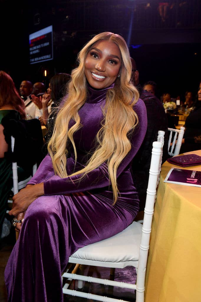 Nene Leakes at an event smiling for a photo as she sits at her table