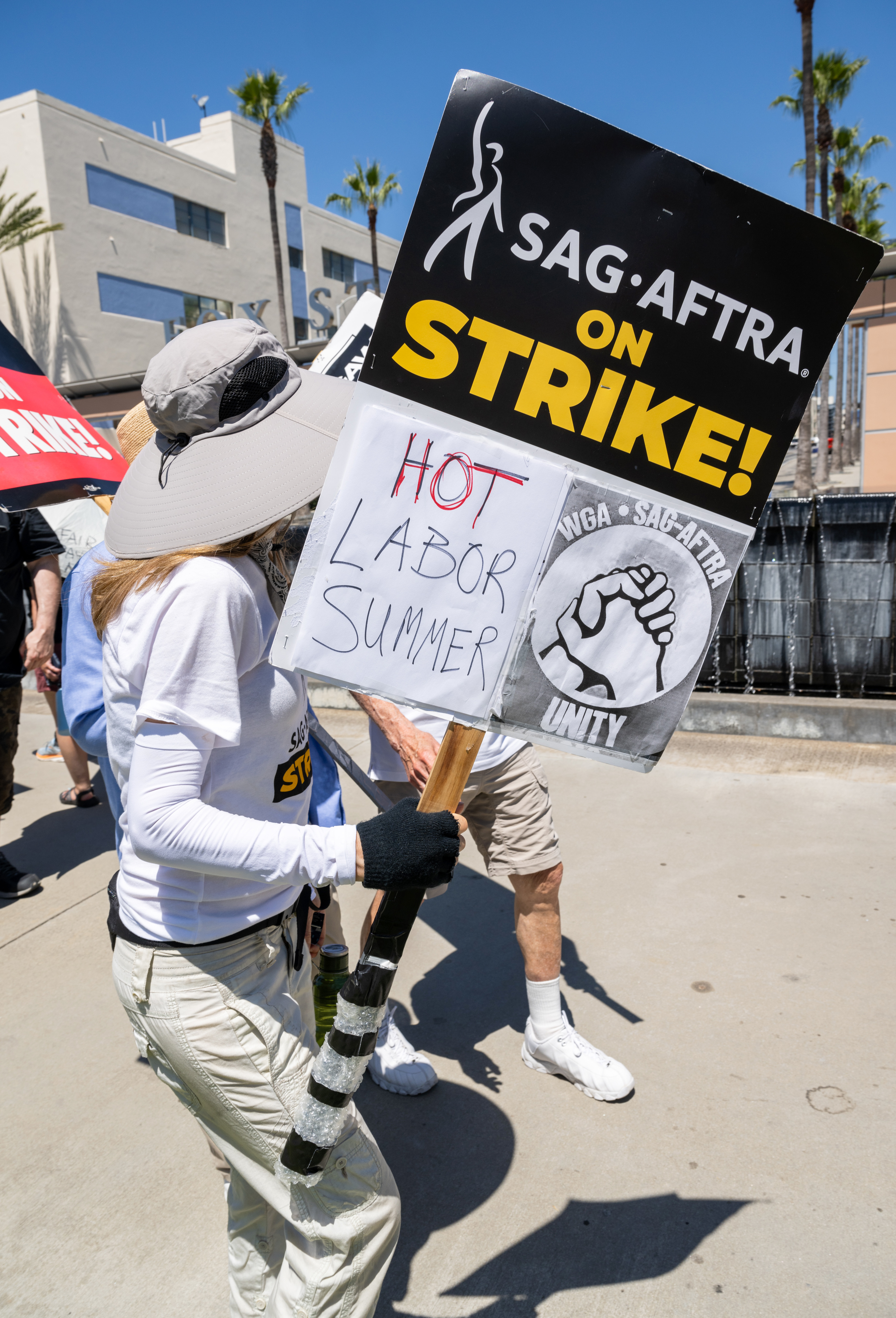 sag aftra member on the picket line with a sign that says hot labor summer