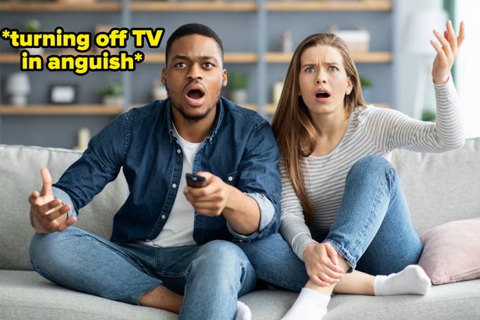 Couple on couch looking upset at what&#x27;s on TV