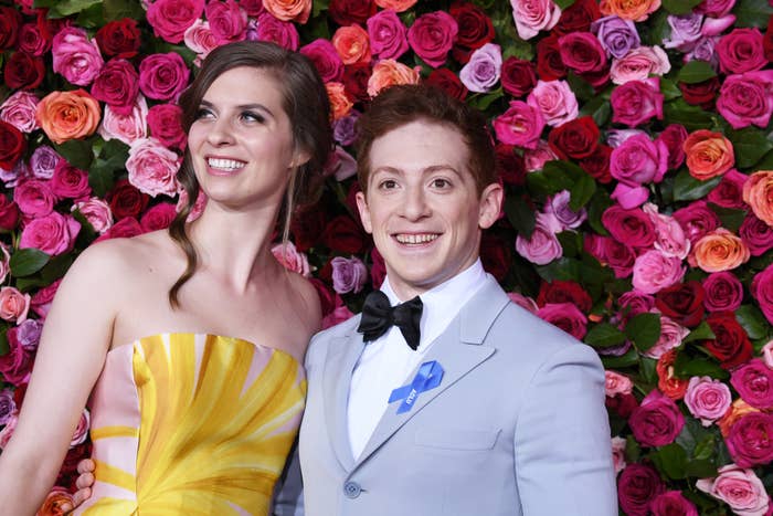 Lilly Jay and Ethan Slater pose together for photos at a red carpet media event in front of a floral wall