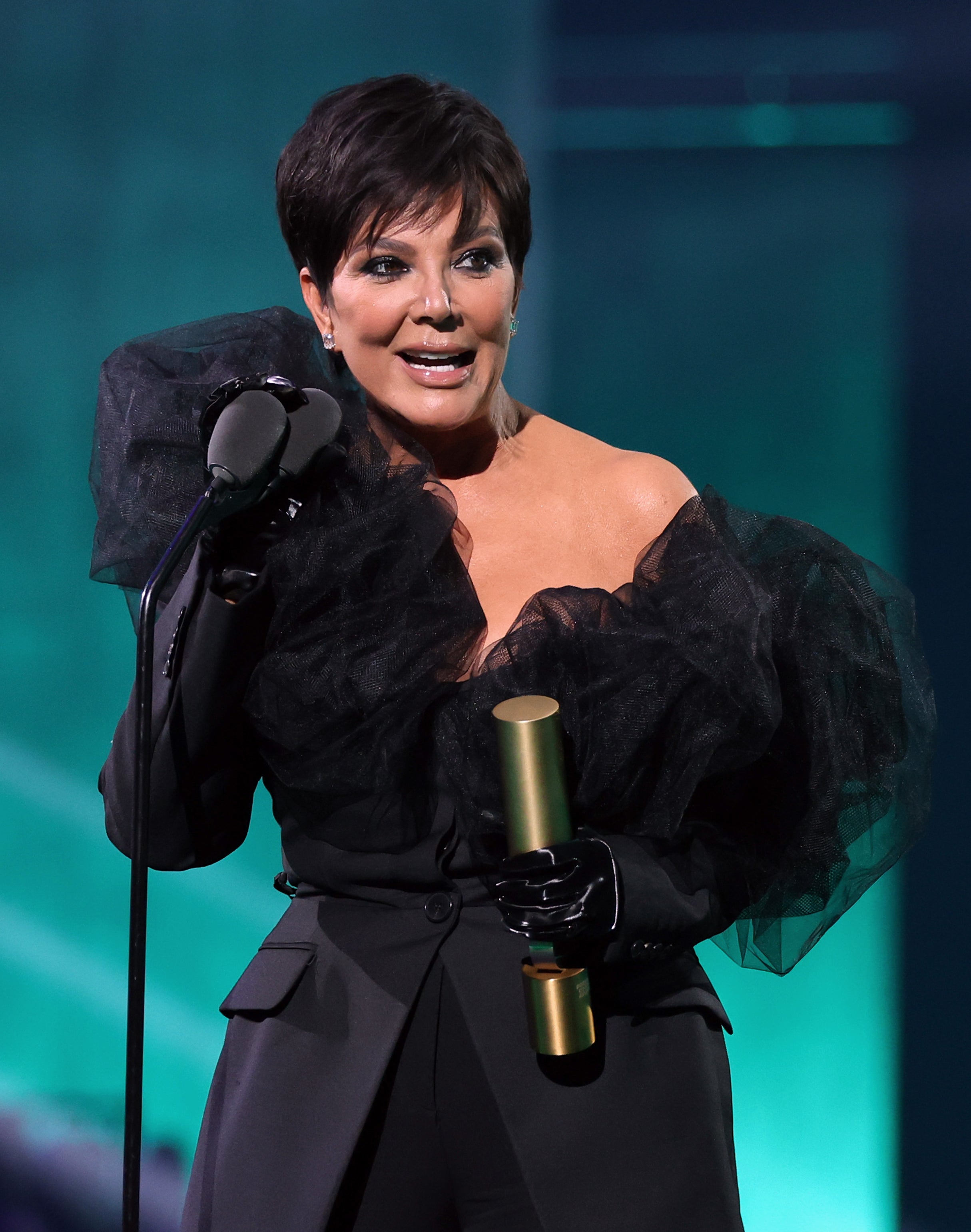 Close-up of Kris at a microphone holding an award