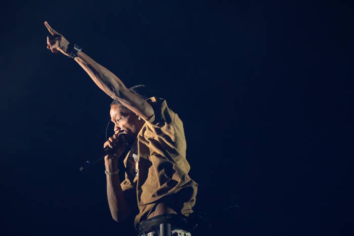 Travis Scott points to the sky as he performs onstage
