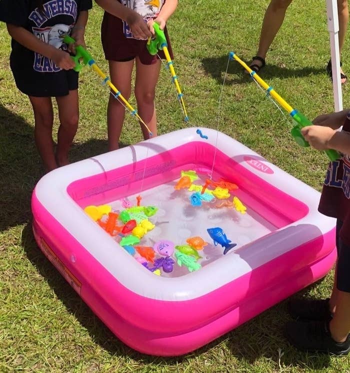 a reviewer photo of kids using the fishing game in a pink inflatable pool