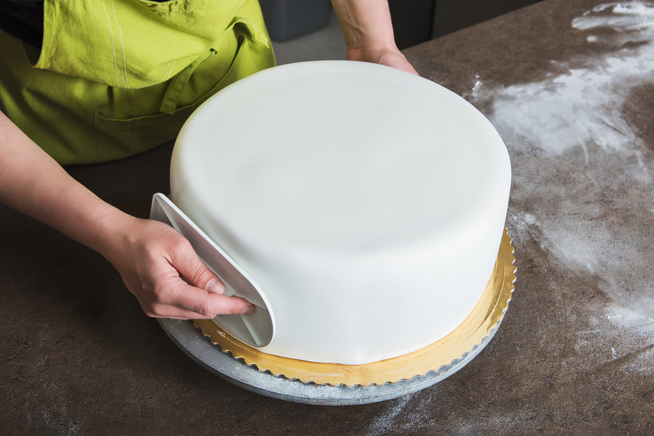 A baker smoothing a round cake