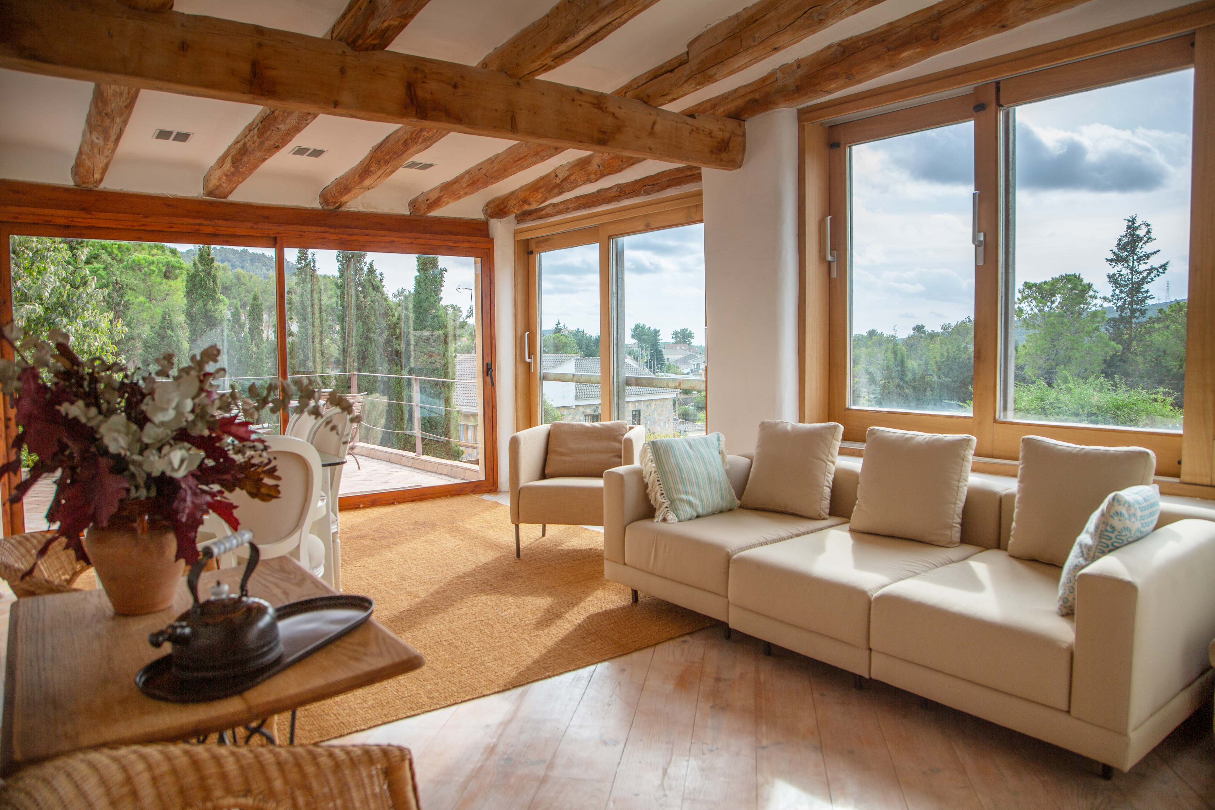 Open concept room with big windows, neutral furniture, and wooden accents