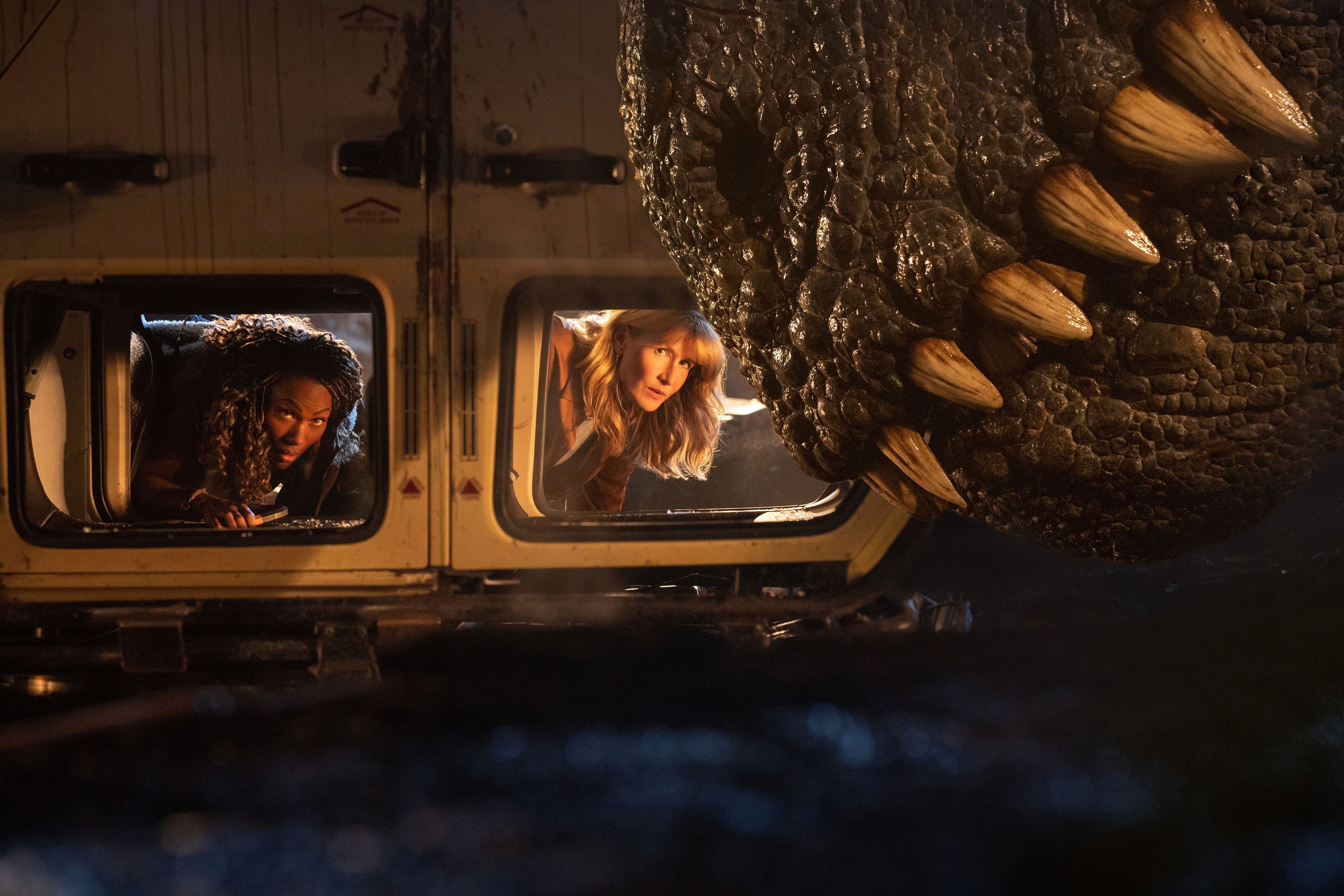 Two women in an overturned vehicle observe a tyrannosaurus rex maw