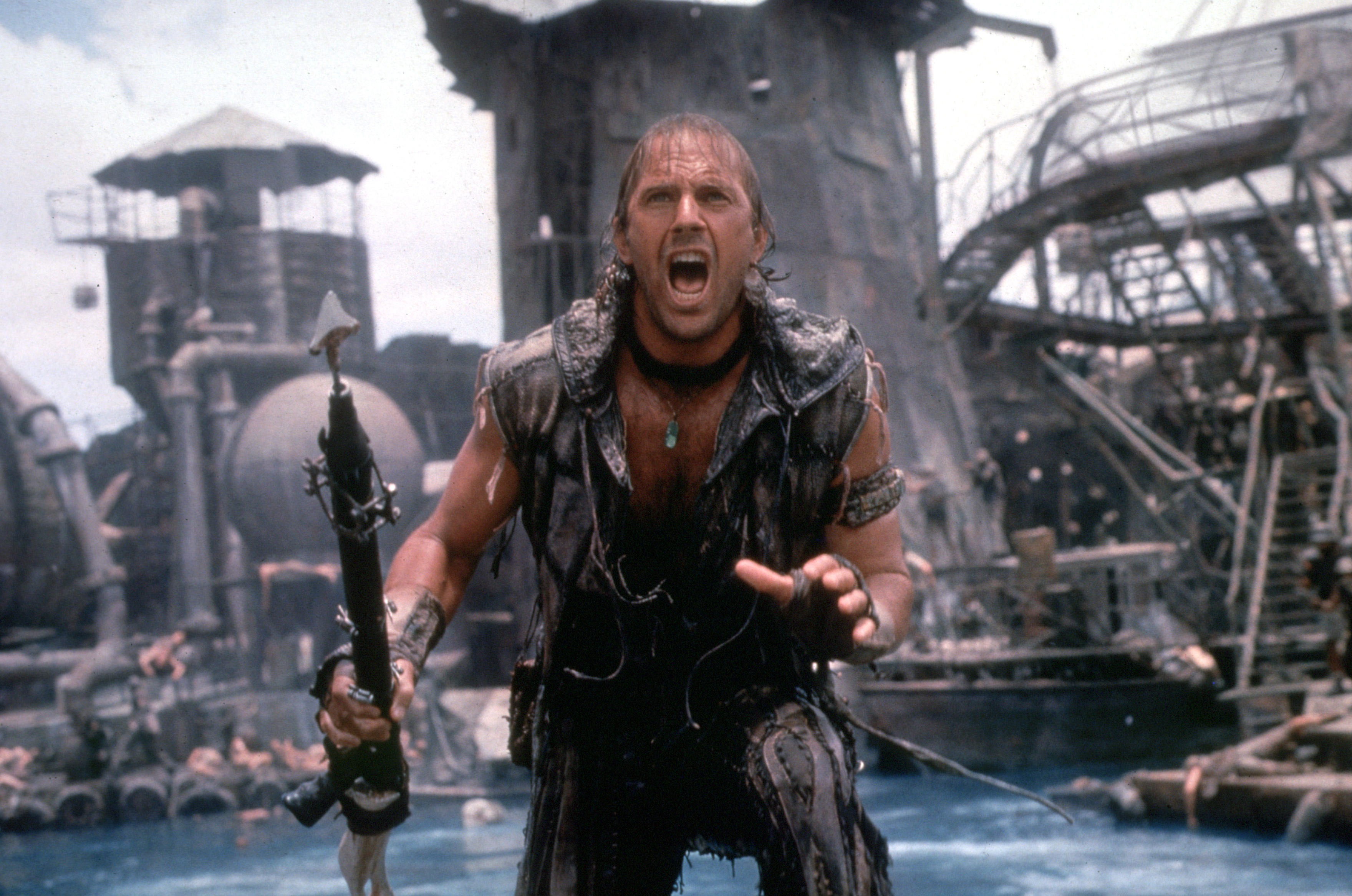 Kevin Costner stands with a harpoon in a floating industrial city