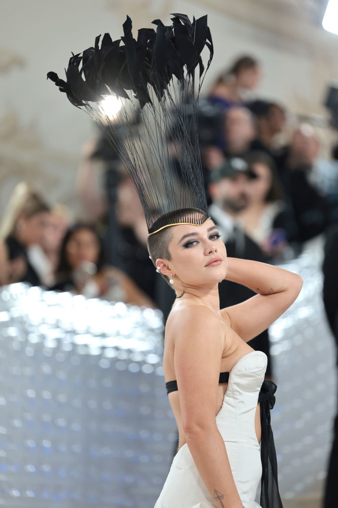 flo at the met gala with a buzz cut and tall feather hat