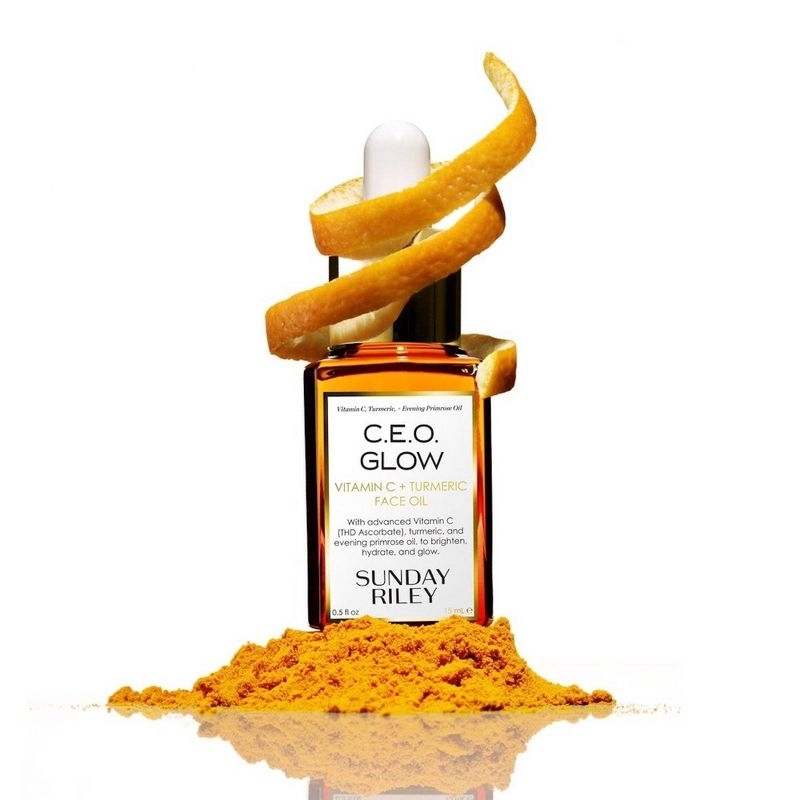 A bottle of face oil with a small pile of turmeric