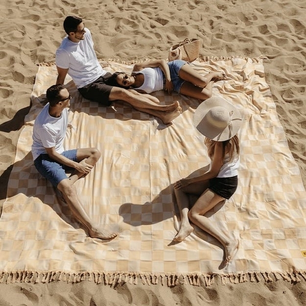 four models sitting on a blanket on the beach